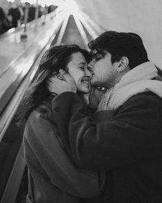 a man and woman kissing on an escalator