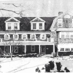 an old black and white photo of a large house with two storyed houses in the snow