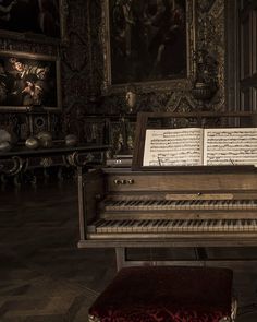 an old piano with sheet music on it in a room filled with paintings and artwork