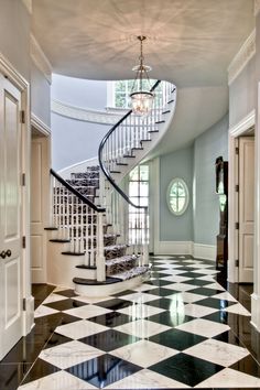 an elegant foyer with black and white checkered flooring, chandelier and stairs