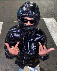 a young boy wearing a black jacket and sunglasses standing in the middle of a street