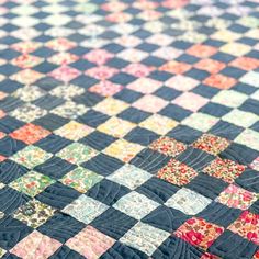 an old quilt is laying on top of a tablecloth that looks like it has been made into a checkerboard pattern