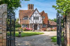 the entrance to a large home with an iron gate and brick pillars leading into it