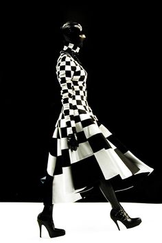 a woman in black and white checkered dress with high heels