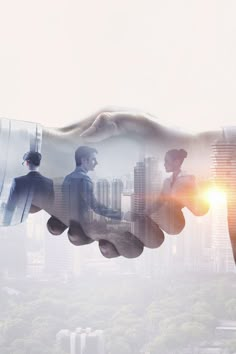 two people shaking hands with cityscape in the background and sunlight shining through them