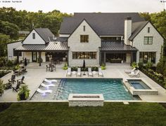 an aerial view of a house with a swimming pool in the foreground and patio furniture on the other side