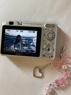 a digital camera sitting on top of a table next to a heart shaped keychain