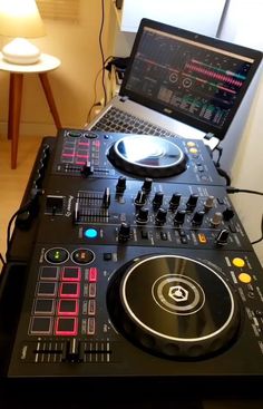 a laptop computer sitting on top of a dj's desk next to a mixer