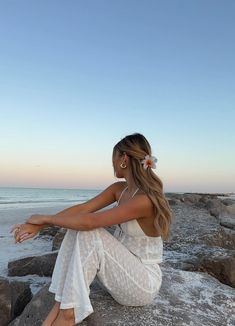 a woman sitting on top of a rock next to the ocean