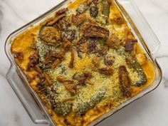 a casserole dish with broccoli and meat in it on a marble table