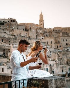 a man and woman standing next to each other holding wine glasses