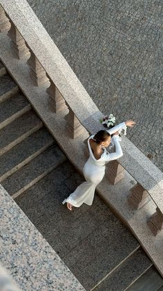 a woman in a white dress is walking down the stairs