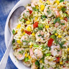 a white bowl filled with shrimp and rice salad on top of a blue table cloth