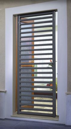 an open sliding door with blinds on the outside and inside, in front of a house