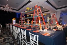 a long table is set up with orange and white plates, candles, and ladders