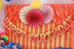 an orange and yellow striped birthday banner with red, white, and blue decorations on it