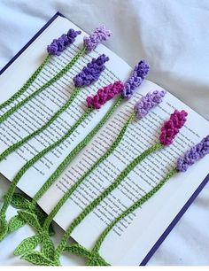 four crocheted flowers sitting on top of an open book