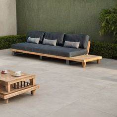 a couch and coffee table sitting on top of a cement floor next to a wall