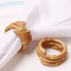 two napkin rings sitting next to each other on top of a white cloth covered table