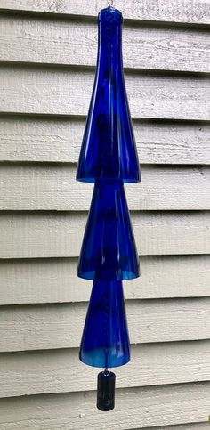 three blue glass vases hanging from a hook on the side of a house's wall