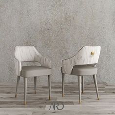 two chairs sitting next to each other on top of a wooden floor in front of a wall