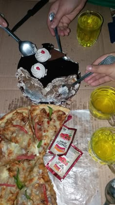 two slices of pizza sitting on top of a table next to drinks and utensils