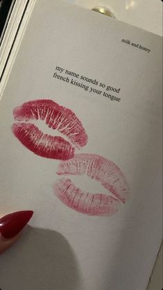 a woman's hand holding a book with two lipstick imprints on the pages