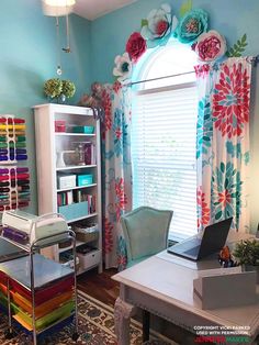 a desk with a laptop on top of it in front of a window filled with curtains