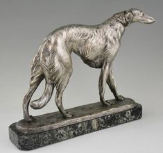 a statue of a dog standing on a marble base with its tail curled in the wind