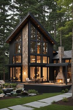 a large house with lots of windows and lights on it's front porch, surrounded by trees