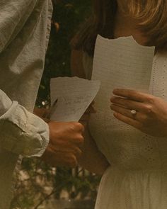 two people are holding papers and looking at each other's hand while standing next to each other