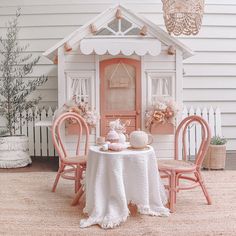 a doll house with two chairs and a table in front of it, set up for a tea party