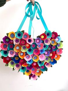 a person holding up a heart shaped origami flower arrangement made from rolled paper