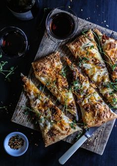 several slices of pizza sitting on top of a cutting board next to some dipping sauces