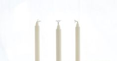 three candles sitting on top of each other in front of a white wall and floor