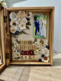 a wooden frame with flowers and photos in it