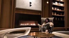 a woman sitting in a chair next to a fire place