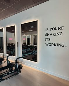 an exercise room with mirrors and treadmills in front of the wall that says if you're shaking, it's working