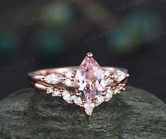 a pink diamond ring sitting on top of a rock