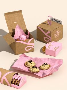 an assortment of cookies and pastries in pink paper bags on a white table top