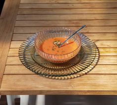 a glass bowl filled with soup on top of a wooden table