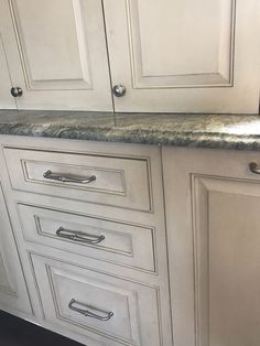 a kitchen with white cabinets and granite counter tops