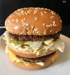 a hamburger with lettuce and cheese on it sitting on top of a white plate