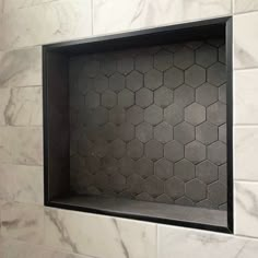 a bathroom with white marble and black hexagonal tiles on the wall, along with a toilet paper dispenser