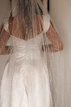 a woman in a white wedding dress is covered with water droplets from the rain coming down her veil