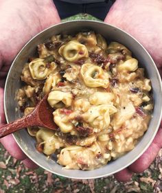 a person holding a bowl filled with pasta and meat