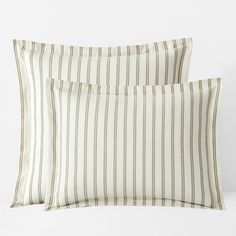 two striped pillows sitting next to each other on top of a white bedding set