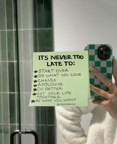 a woman taking a selfie in front of a mirror with a note attached to her phone