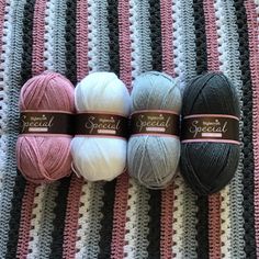 three skeins of yarn sitting on top of a striped blanket next to each other