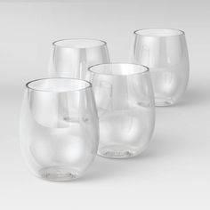 three clear wine glasses sitting next to each other on a white surface with one empty glass in the middle